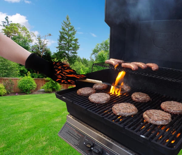 Cooking with BBQ glove with burgers and flames